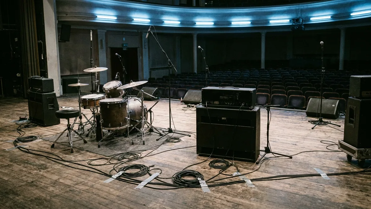 Leere Musicalbühne mit Bandinstrumenten, Schlagzeug und Mikrofonständern im Halbdunkel