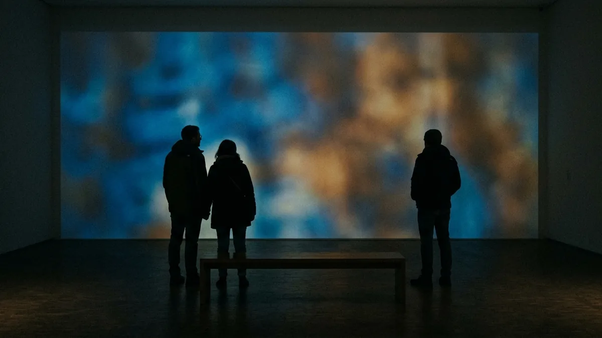 Besucher als Silhouetten in einem dunklen Ausstellungsraum mit Projektion