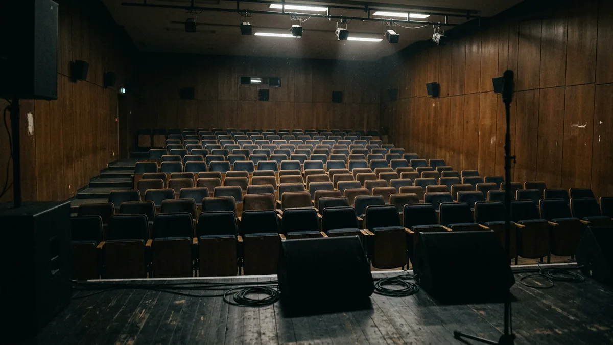 Leerer Konzertsaal mit Bestuhlung, von der Bühne aus fotografiert, Arbeitslicht